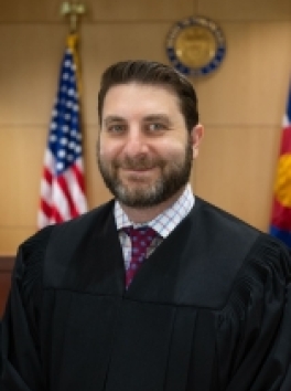 Photo of White Male Judge in front of US Flag and Colorado Court Seal 