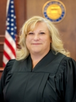 Photo of White Female Judge in Front of US Flag and Colorado Court Seal