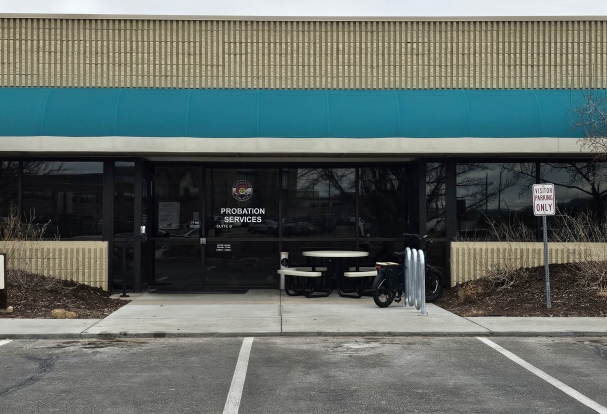 Parking lot and front of Midpoint Office. Green awning on beige building.